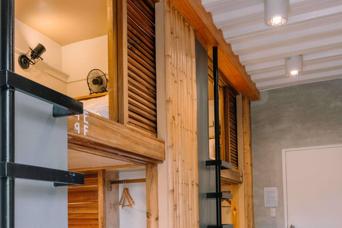 A bunk bed with a wooden ladder, a small shelf, and a hanging bag.