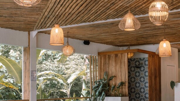 A pool area with wooden ceiling, hanging wicker lights, and a view of tropical foliage. - Happiness Hostel Siargao (General Luna)