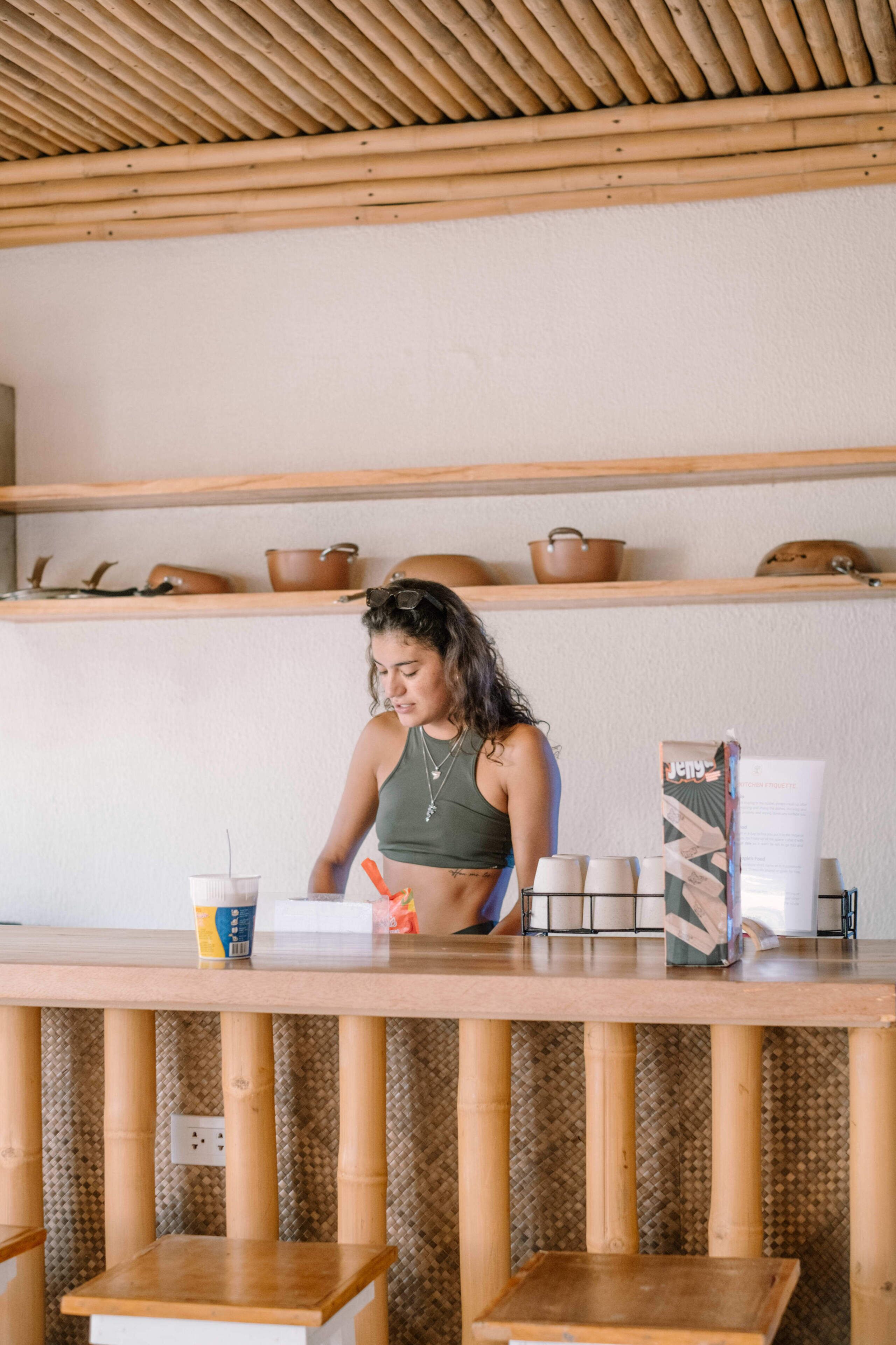 A person seated at a wooden table with a cup and a box on it.