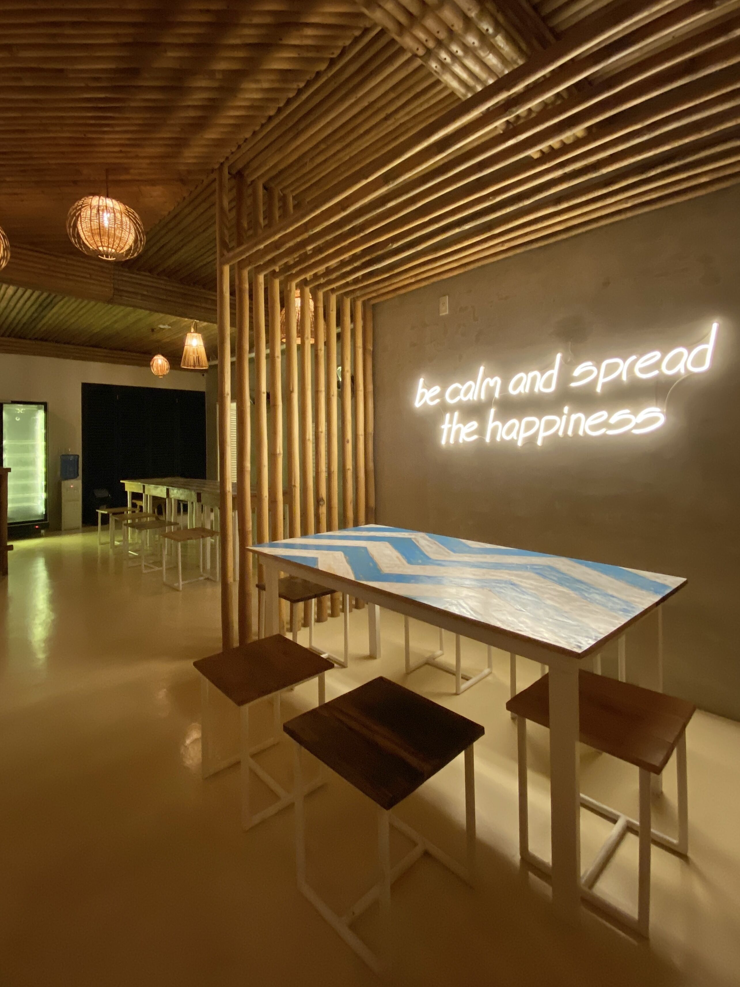A modern interior with a long table and benches, a wall with a motivational quote, and a wooden ceiling.