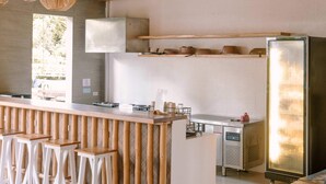 A modern kitchen with a central island, bar stools, and a large refrigerator. - Happiness Hostel Siargao (General Luna)