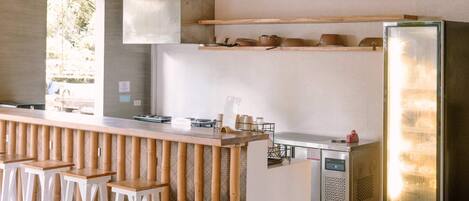 A modern kitchen with a central island, bar stools, and a large refrigerator.