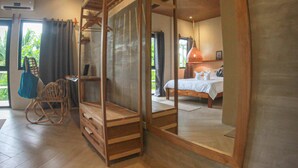 A bedroom with a bed, a wooden chair, a desk, and a large mirror. - Happiness Hostel Siargao (General Luna)