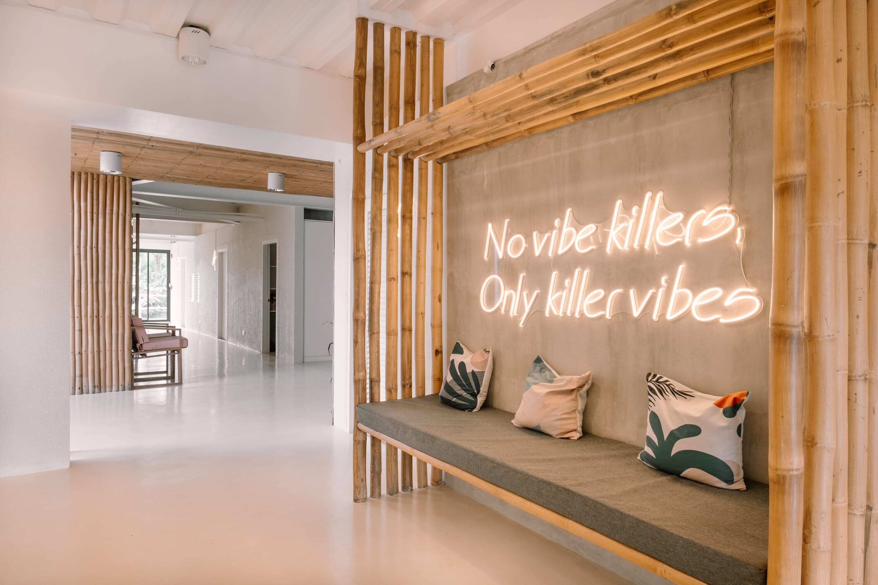 A modern interior with a bench, pillows, and a neon sign.