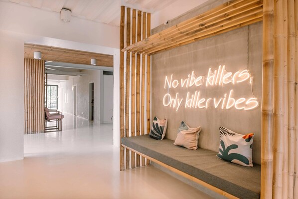 A modern interior with a bench, pillows, and a neon sign.