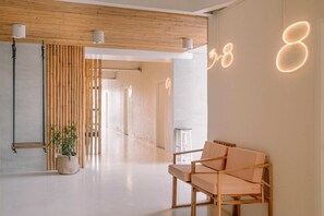A modern interior with a wooden ceiling, a bench, a potted plant, and illuminated numbers on the wall.