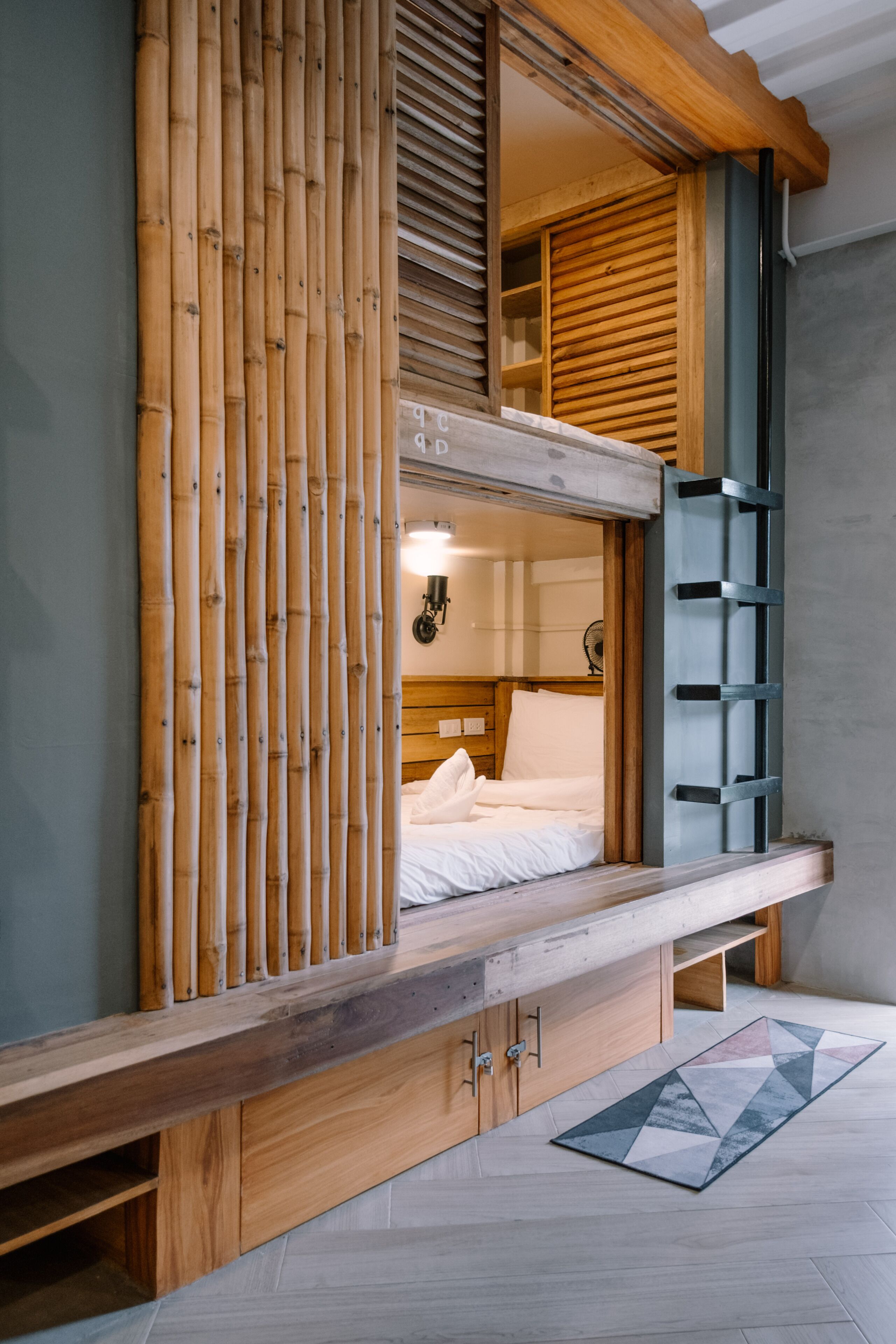 A room with a bed, wooden headboard, and a bamboo screen.