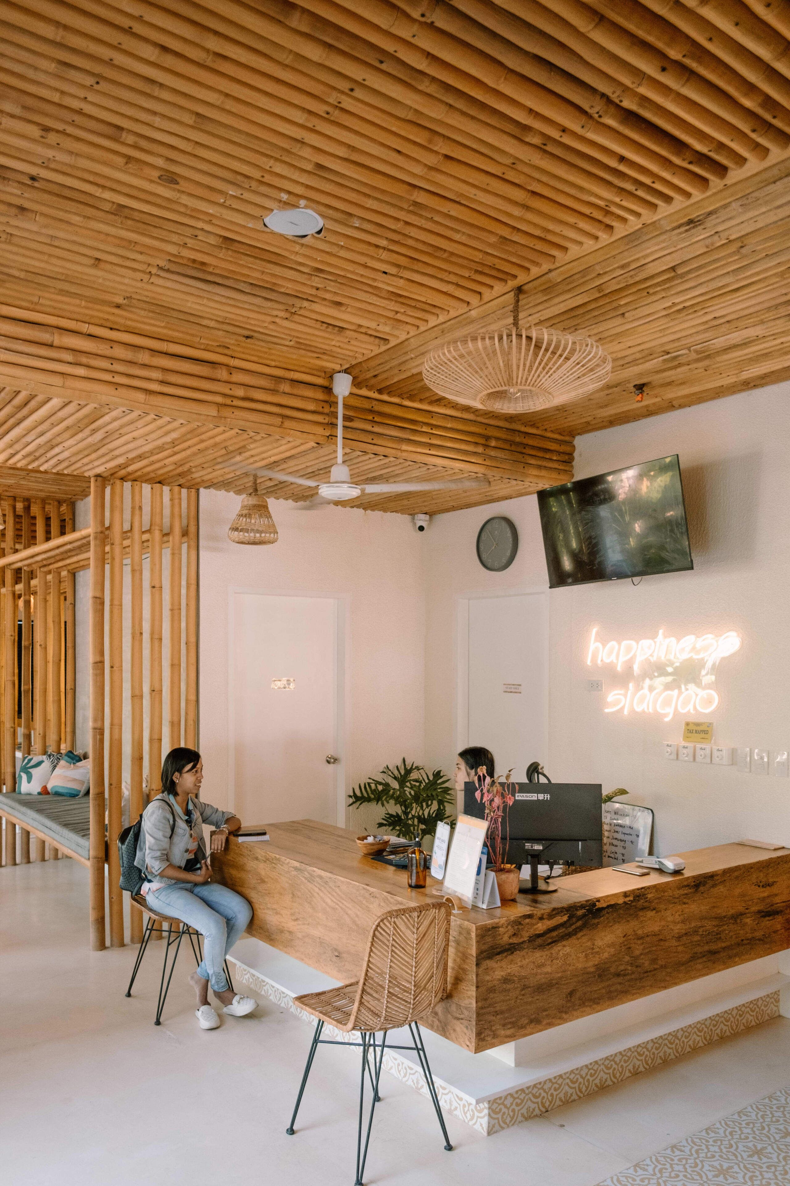 A reception desk with a wooden finish, a television mounted on the wall, and a neon sign.