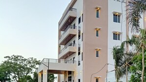 A multi-story building with a covered entrance, a fire hydrant, and a well-maintained lawn.