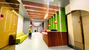 A reception area with a wooden counter, green walls, and a yellow sofa.
