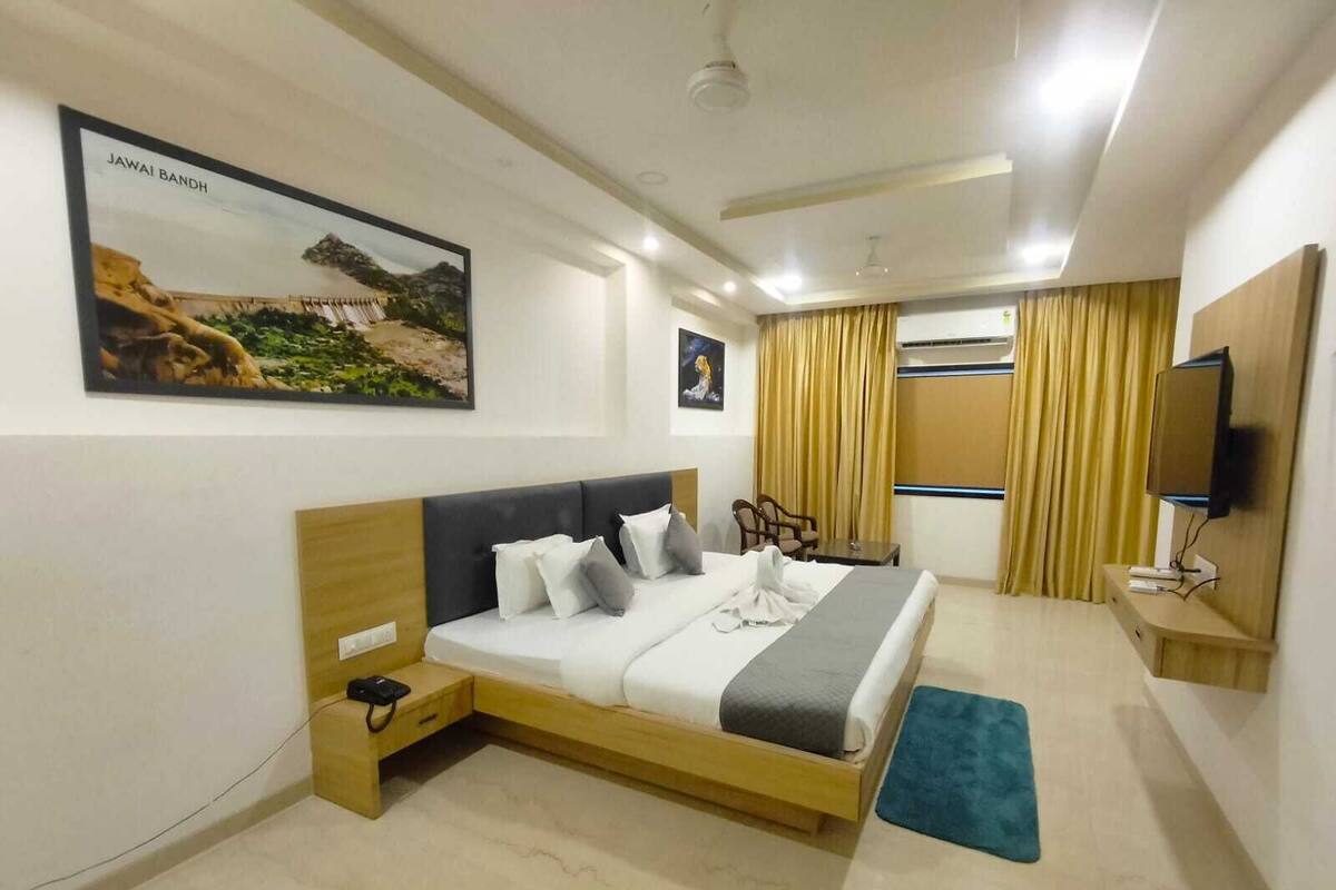 Una habitació d'hotel moderna amb un llit gran, un escriptori, una televisió i un quadre d'un paisatge.