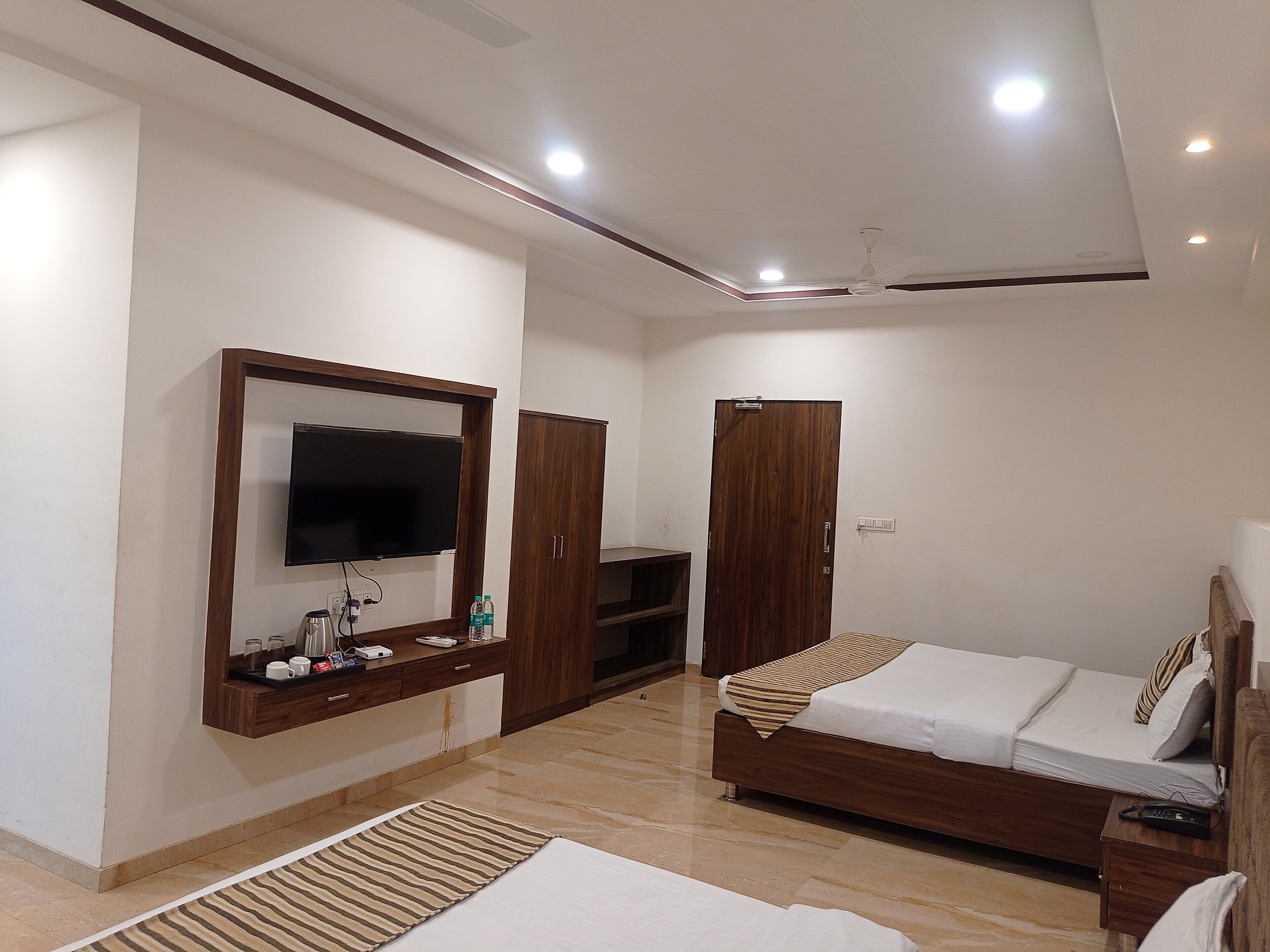 Une chambre moderne dotée d’un téléviseur à écran plat, d’une armoire en bois et d’un lit recouvert d’une couvre-lit à rayures.