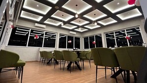 A conference room with a modern ceiling design, large windows, and green chairs.