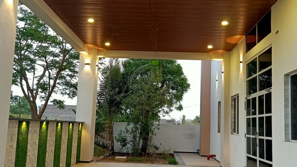 A covered outdoor area with a tiled floor, wooden ceiling, and walls with green vertical accents.