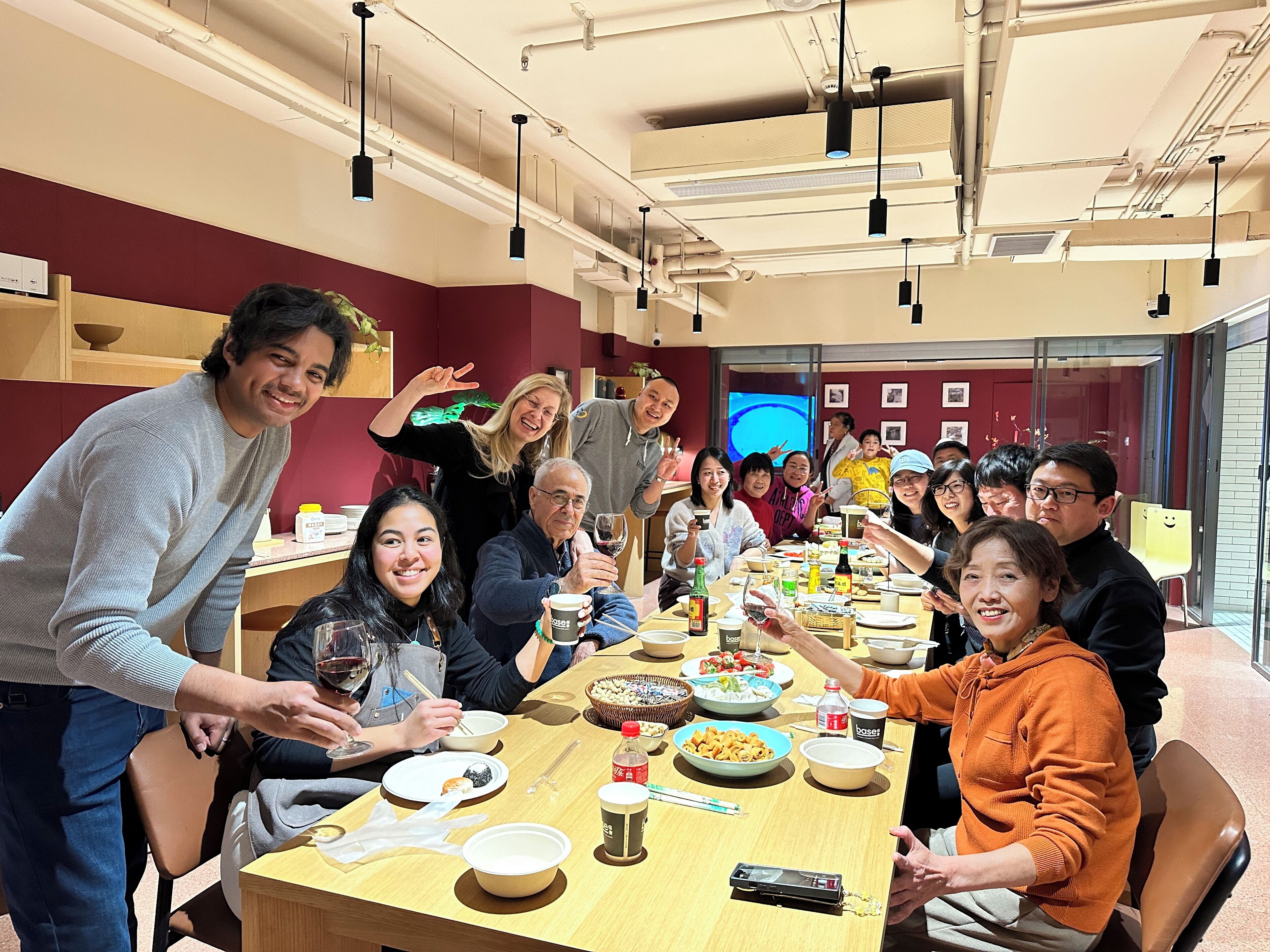 A group of people seated around a long table in a room with a high ceiling and visible ductwork.