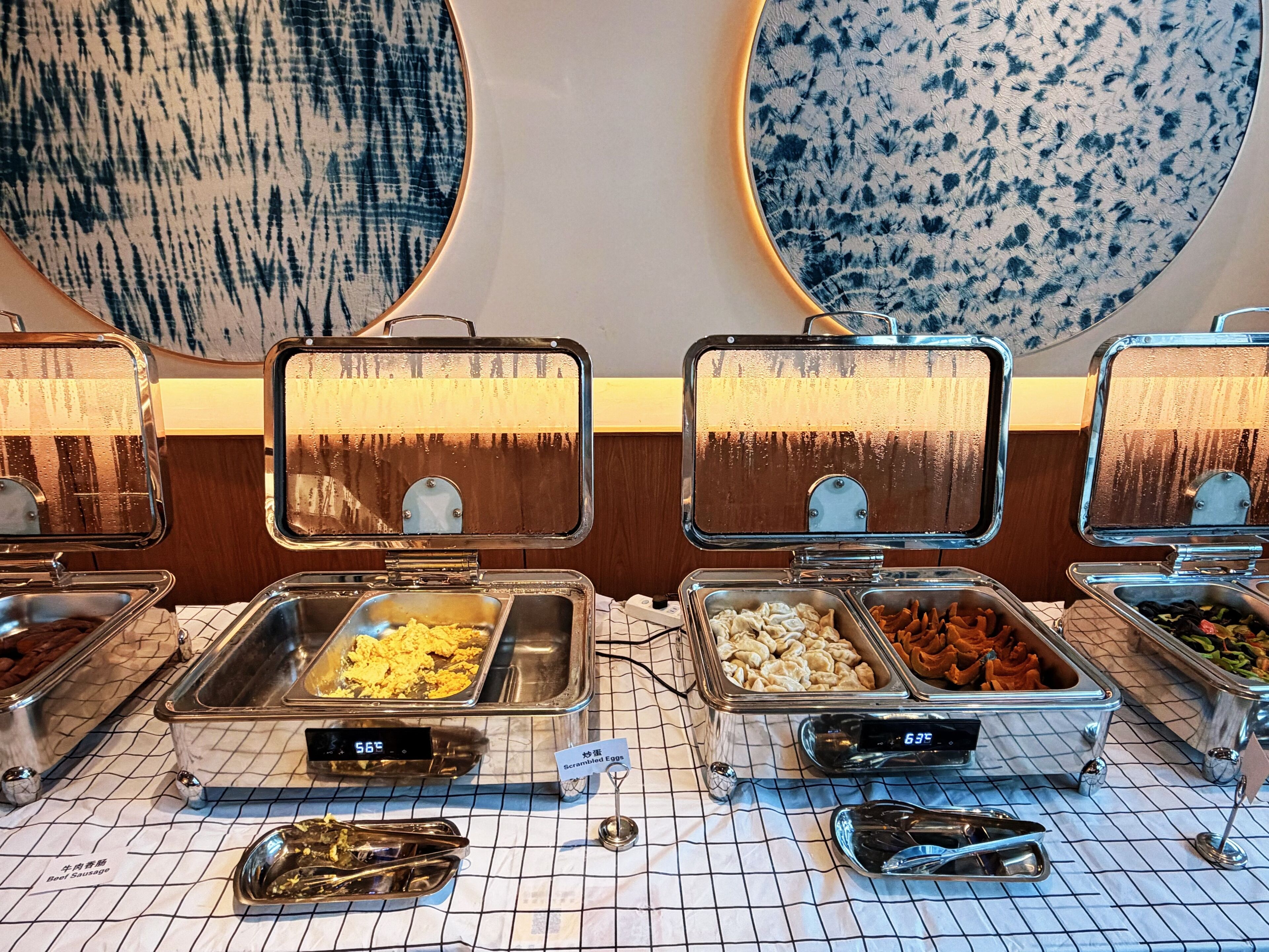 A buffet with various food items, including scrambled eggs and sausage, with temperature displays.