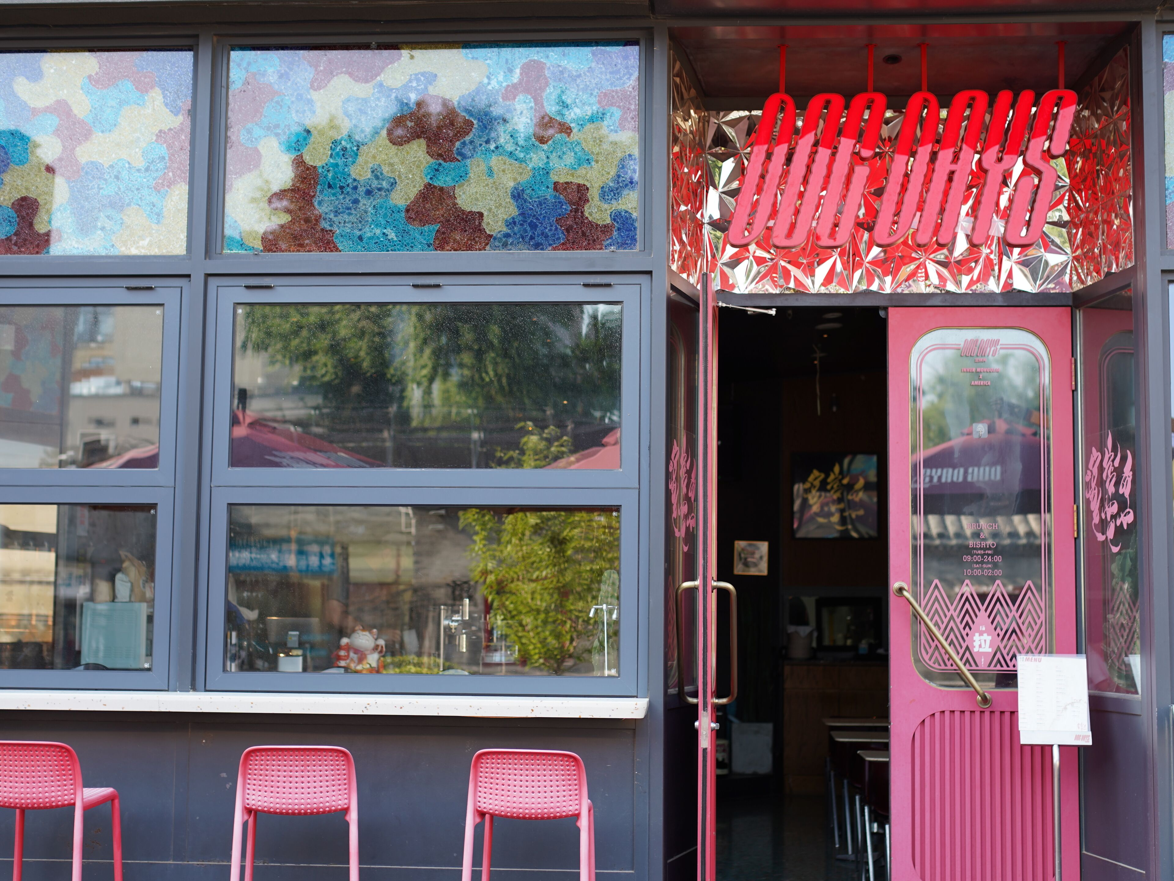 Un restaurante con fachada rosa y escaparate que muestra obras de arte coloridas.