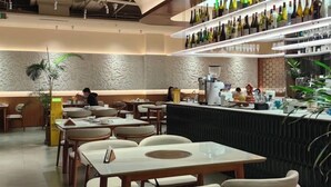 Un restaurant moderne doté d’un bar, de plusieurs espaces pour s’asseoir et d’une variété de bouteilles exposées.