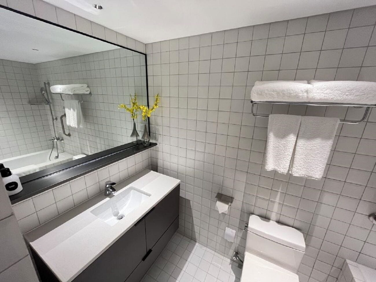 A modern bathroom with a white sink, mirror, and toilet.