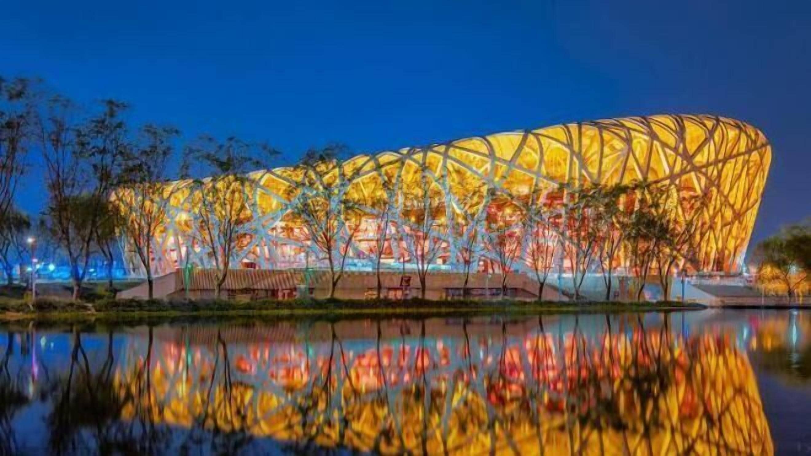 A large, modern stadium with a distinctive, lattice-like roof structure.