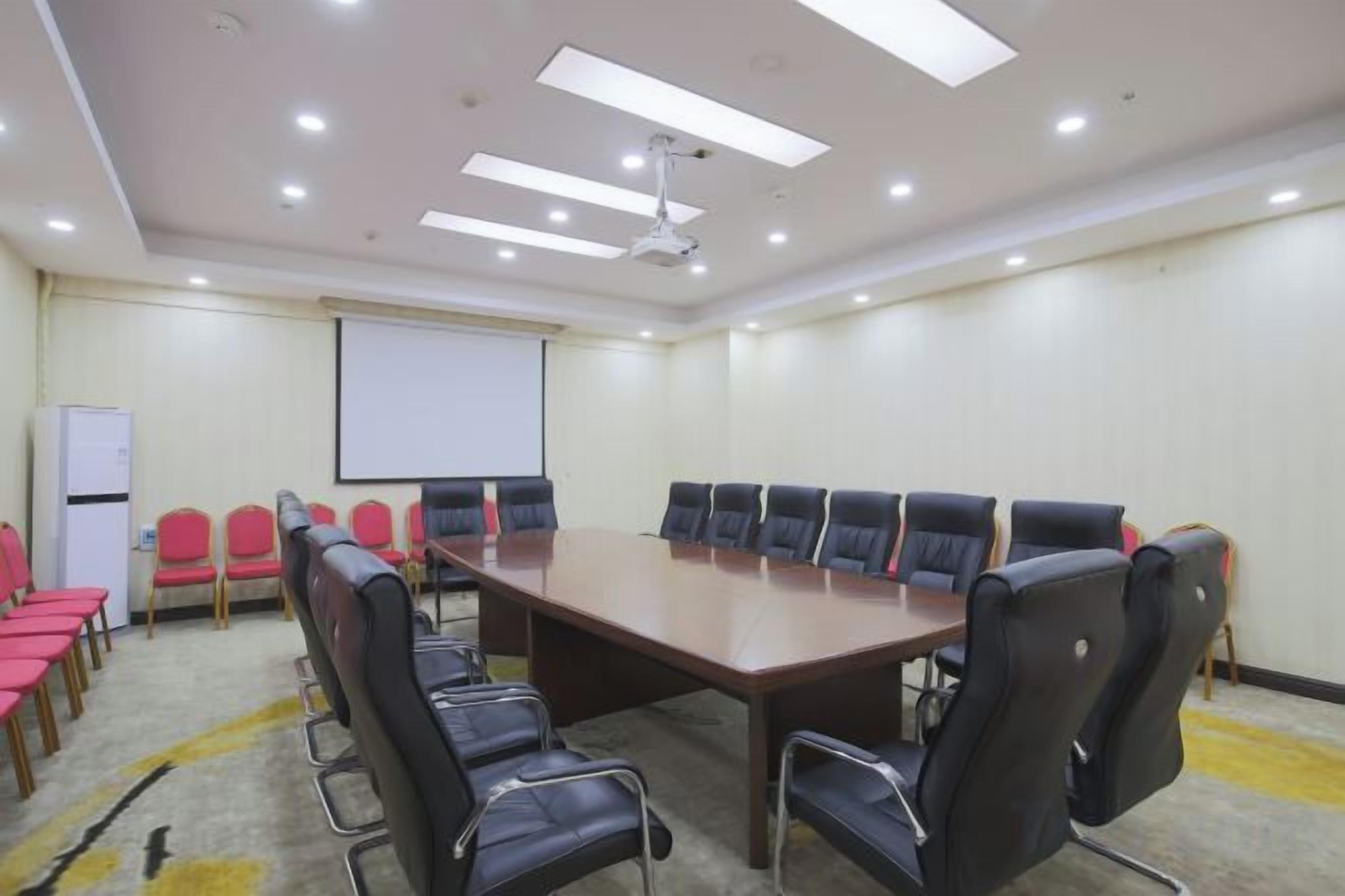 A conference room with a large table, chairs, a projector screen, and a whiteboard.