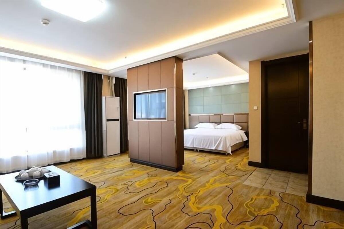 Een hotelkamer met een bed, een televisie, een bureau en een groot raam.