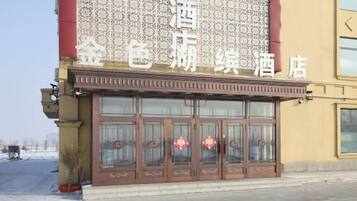 A hotel facade with a large sign, multiple doors, and decorative elements.