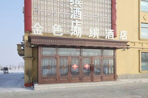 Fachada de hotel com uma grande placa, várias portas e elementos decorativos.