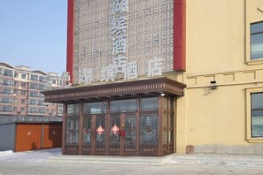 Een hotelgevel met een groot bord, traditioneel Chinees architectuur en een moderne ingang.