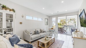 Una sala de estar moderna con un sofá, una mesa de centro y un mueble con objetos decorativos.