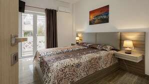 A modern bedroom with a bed, bedside lamps, a TV, and a cityscape painting. - Villa panagiotis (Κίσσαμος)