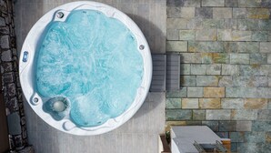A hot tub with a stone wall backdrop. - Villa panagiotis (Κίσσαμος)