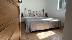 Une chambre à coucher avec un lit, une fenêtre, une porte et un luminaire au plafond.