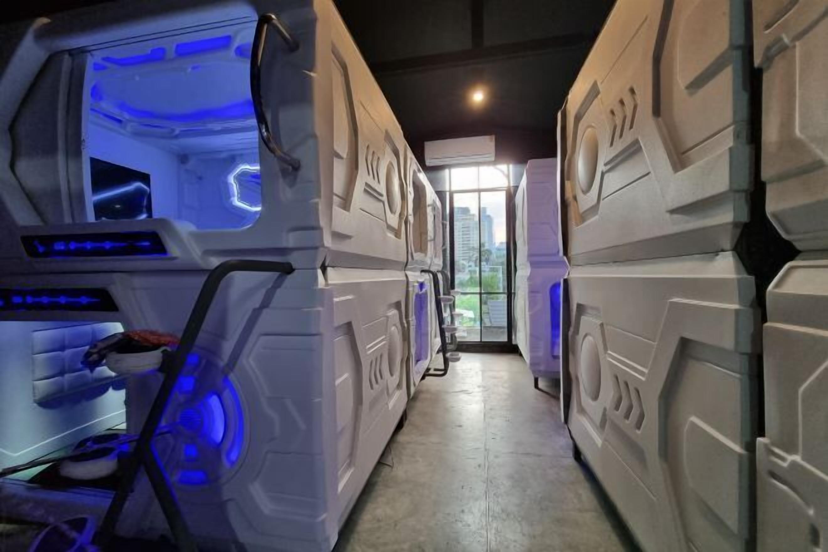 A corridor with stacked bunk beds and a blue-lit room on the left.