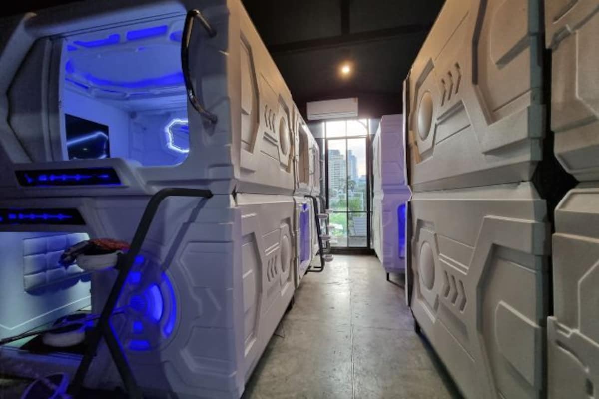 A corridor with stacked bunk beds and a blue-lit room on the left.