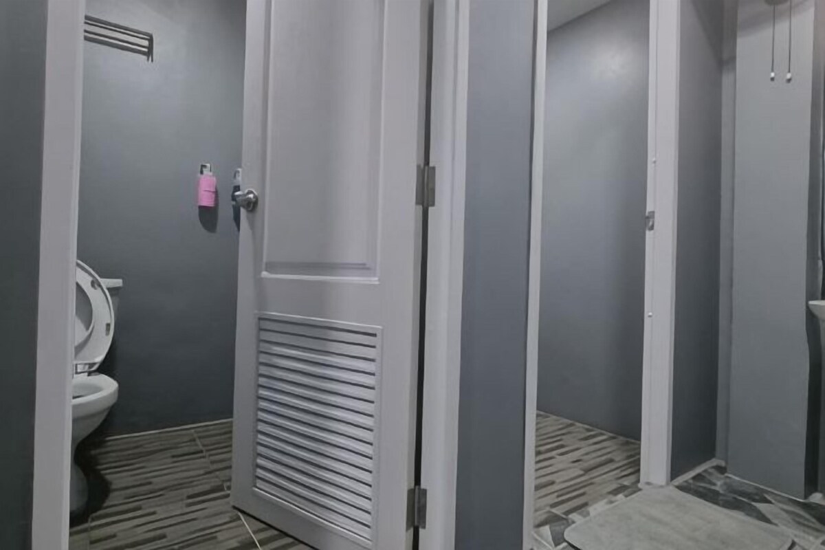 A bathroom with a toilet, a door with a handle, and a patterned floor.