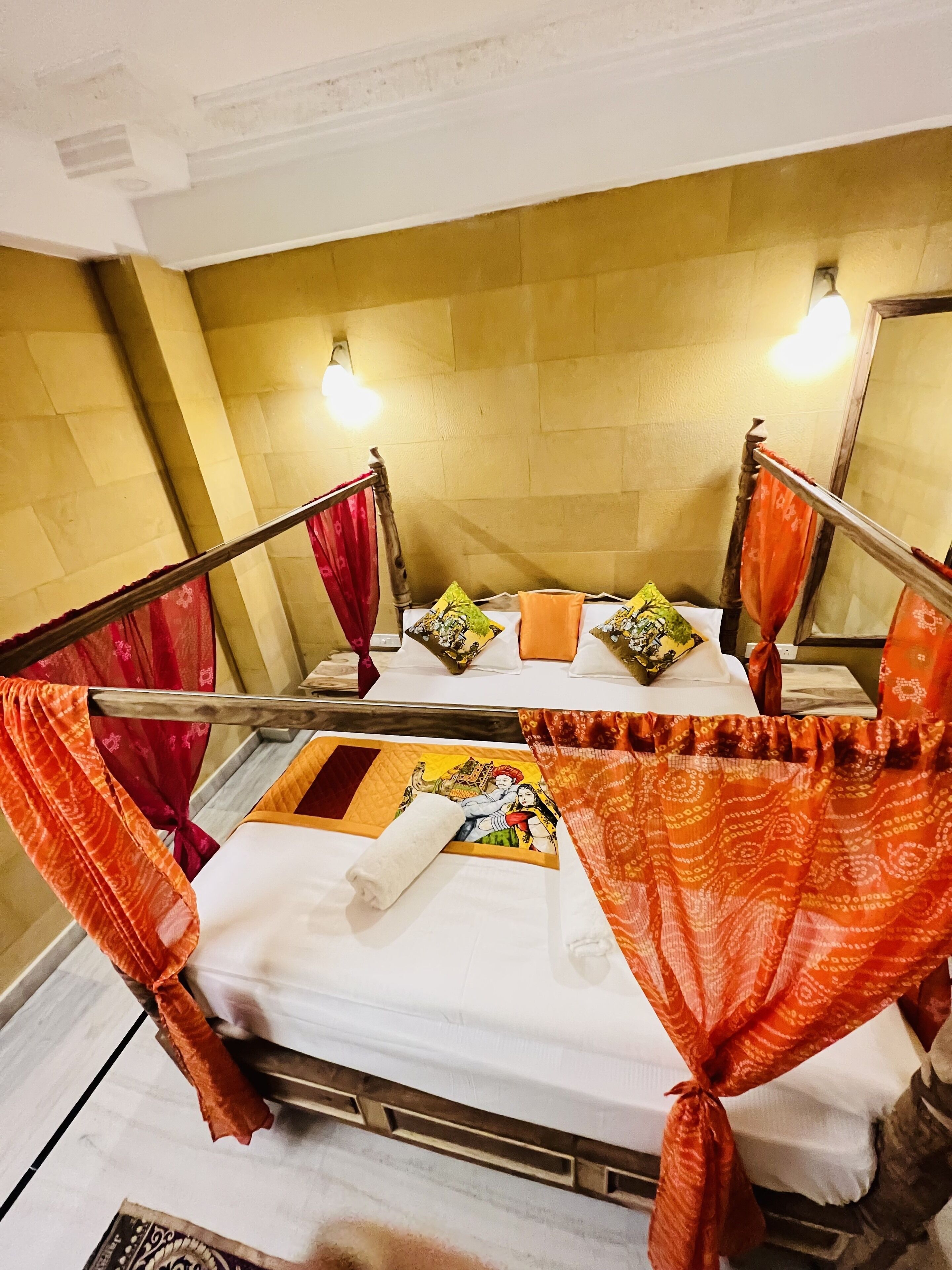 Una habitación con dos camas, cada una con dosel y almohadas. El piso es de baldosas y el cabecero es de madera.