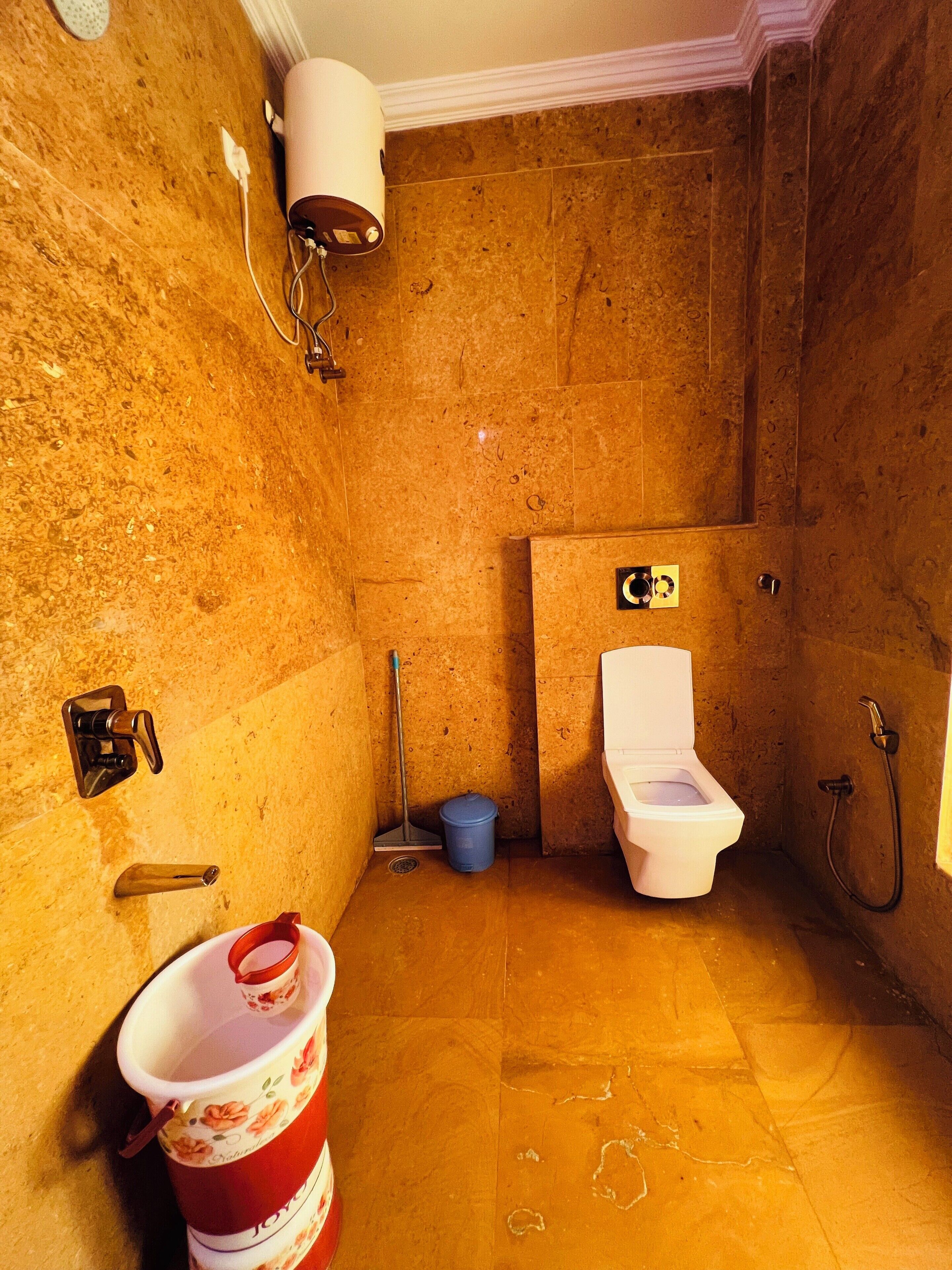 A bathroom with a shower, toilet, and a bucket.