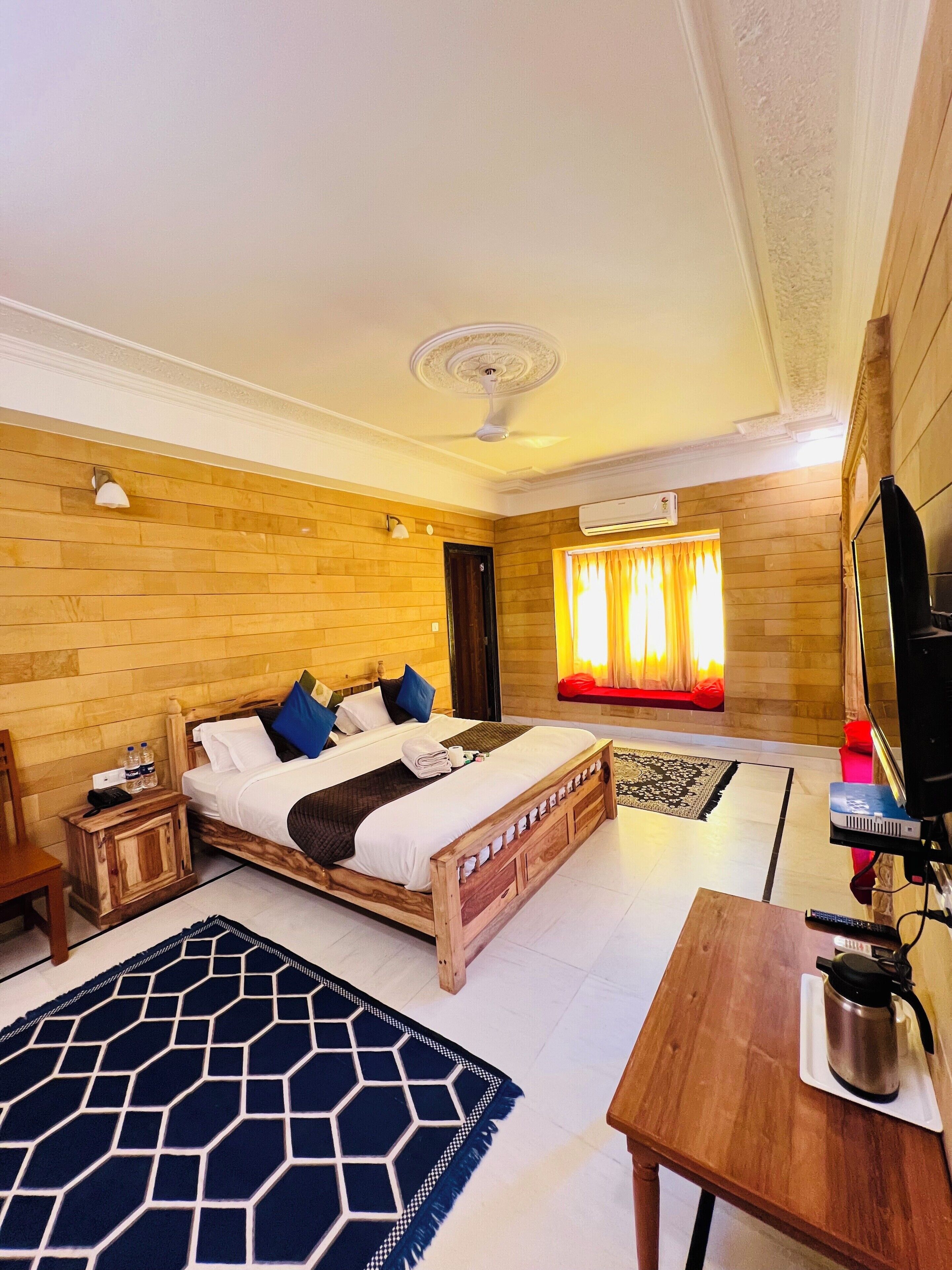 A hotel room with a wooden bed, a TV, a coffee table, and a window with curtains.