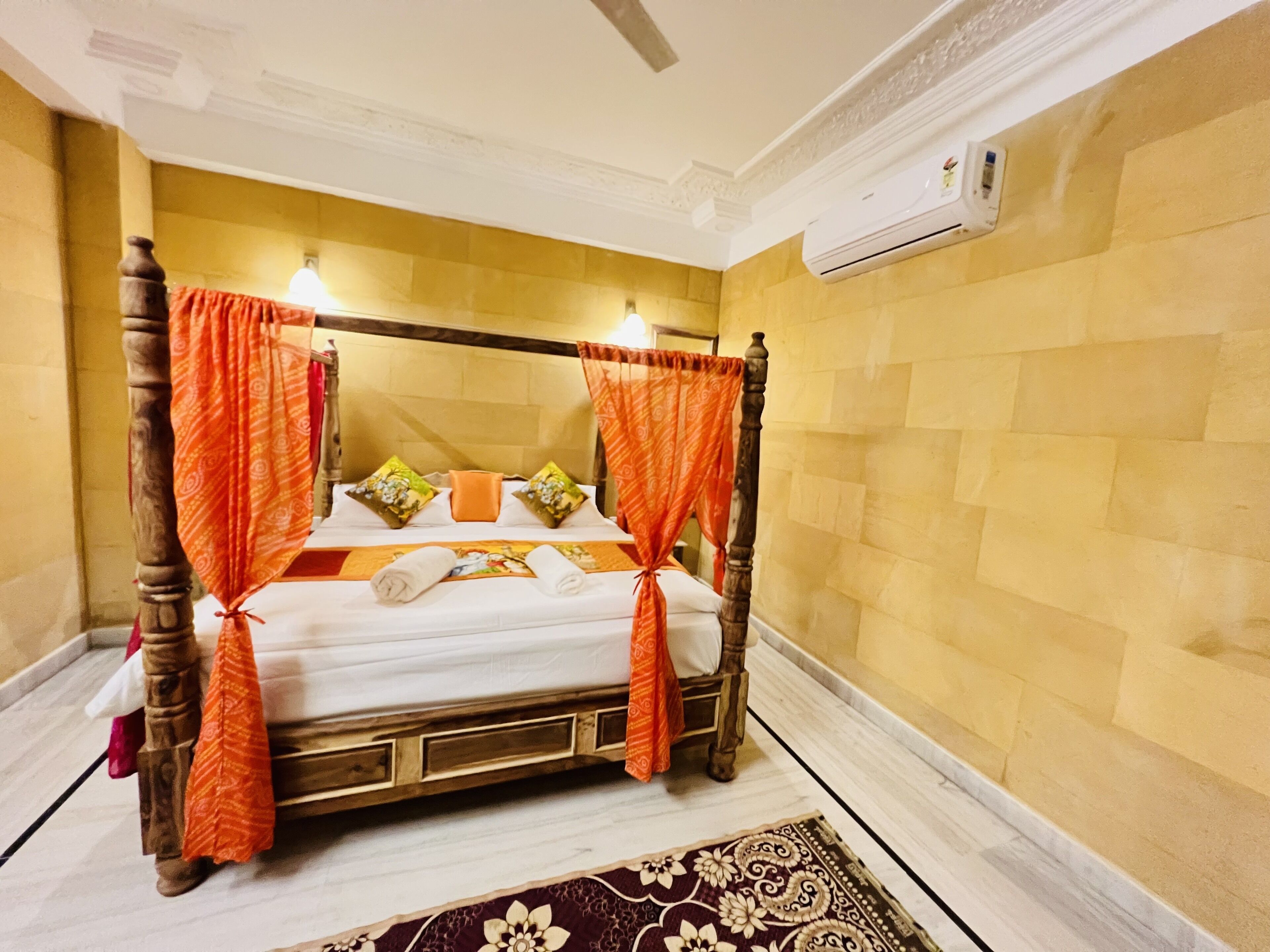 A four-poster bed with a canopy, a marble floor, and a patterned rug.