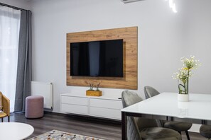 Relax in this stylish living space with a large flat-screen TV, dining area, and cozy seating options.