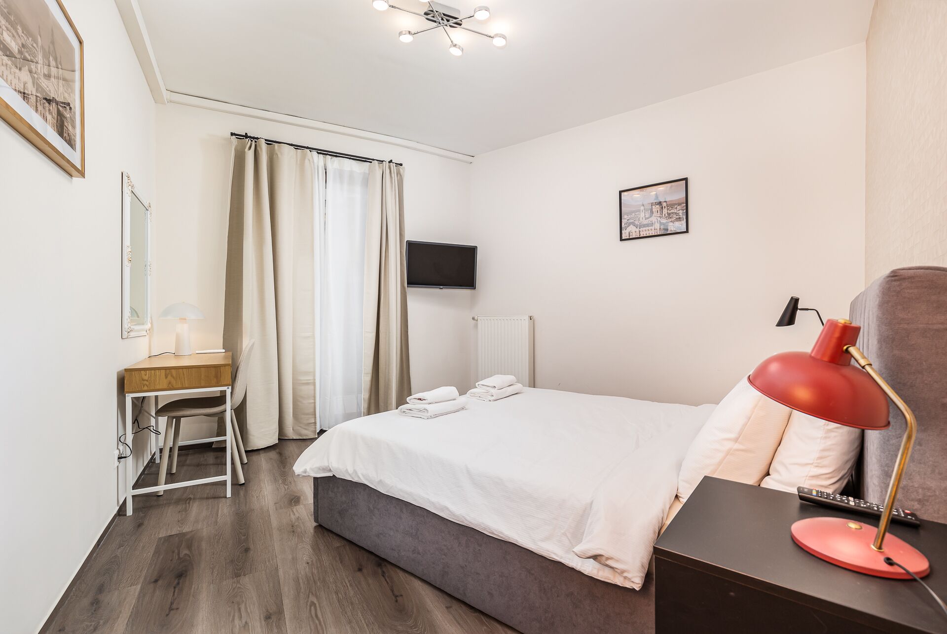 Een hotelkamer met een bed, een bureau met stoel, een televisie en een rode lamp.