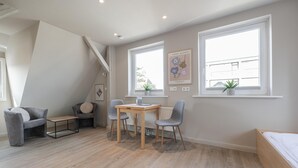 Un dormitorio moderno con cama, escritorio, dos sillas y un radiador.