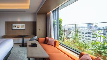 Et moderne hotelværelse med stort vindue, sofa, seng og et lille bord.