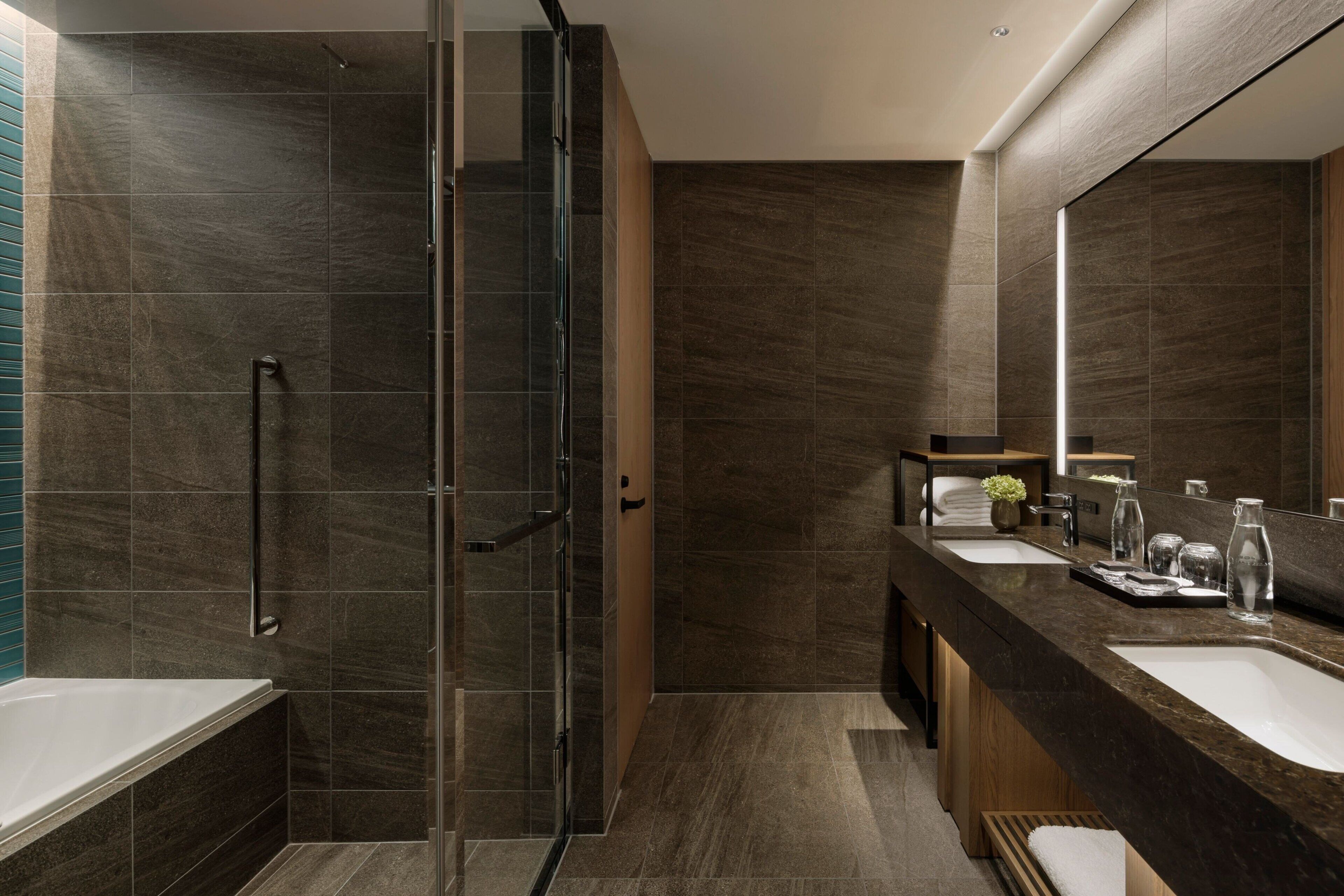 A modern bathroom with a glass shower enclosure, a double sink vanity, and a large mirror.