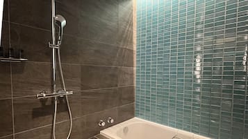 Un baño con bañera, ducha y pared de azulejos.