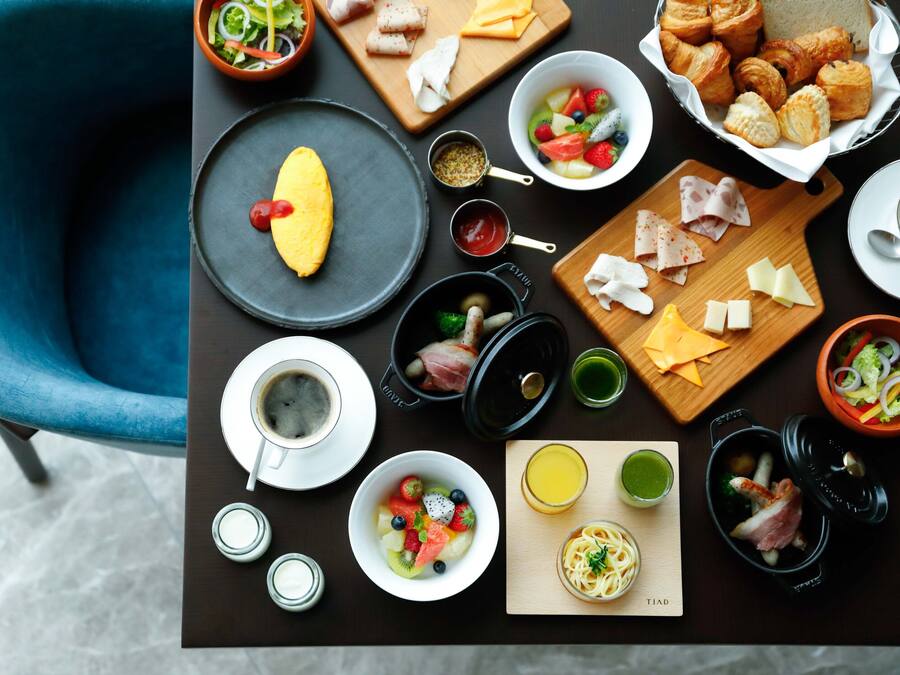 A breakfast table with various food items, including eggs, pastries, and a bowl of fruit.