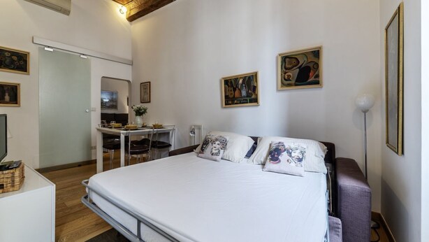 A bedroom with a bed, a desk, and chairs. There are paintings on the wall. - Minerva 5 - FromHometoRome (Roma)