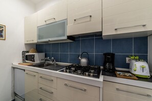 A compact kitchen with white cabinets, a gas stove, a microwave, and a toaster.