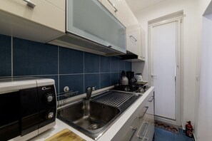 A compact kitchen with a gas stove, a built-in oven, and a stainless steel sink. - Minerva 5 - FromHometoRome (Roma)